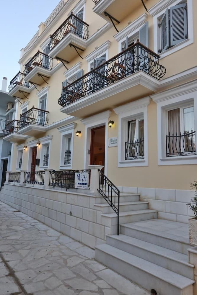 A charming European-style building with elegant balconies, stone steps, and warm lighting invites travelers to explore its cozy ambiance as an ideal accommodation spot.