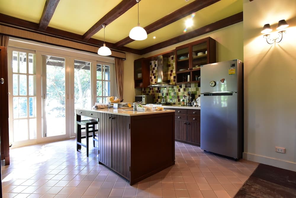 A cozy kitchen with wooden beams, tiled floors, and a central island invites travelers to enjoy home-cooked meals in a warm, inviting atmosphere, perfect for a relaxing vacation rental experience.