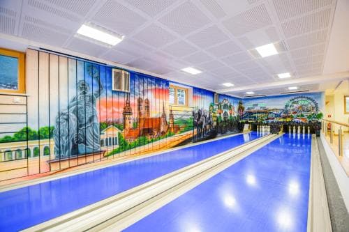 A vibrant indoor bowling alley features a mural of iconic landmarks, creating a lively and colorful atmosphere ideal for family entertainment and leisure activities.