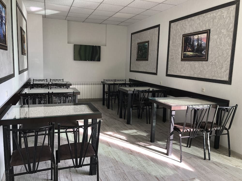 A cozy indoor dining area features modern tables and chairs under bright sunlight streaming through windows, adorned with framed artwork on white walls, ideal for travelers seeking a quiet café or small restaurant experience.