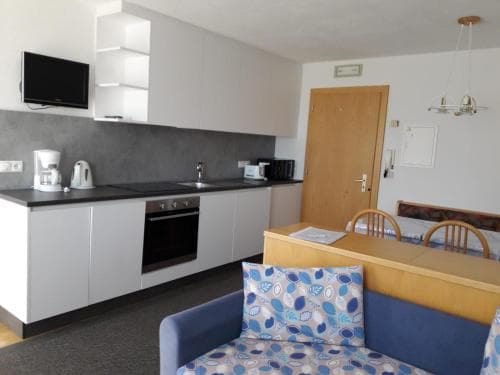 A cozy studio apartment featuring a compact kitchenette with modern appliances, a dining area, and a comfortable seating space, ideal for travelers seeking a functional and homely stay in an urban setting.