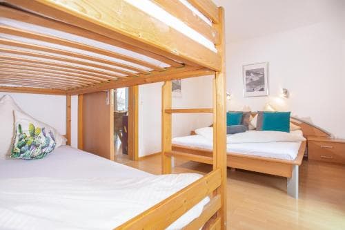 A cozy hostel room with wooden bunk beds, a neatly made double bed, and soft lighting creates a welcoming atmosphere ideal for budget travelers seeking comfort and simplicity.