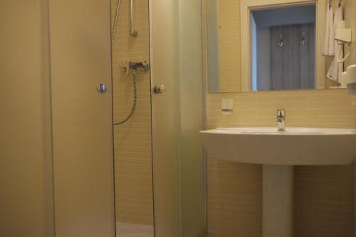 A cozy hotel bathroom features a modern shower stall, sleek sink, and mirrored cabinet, creating a clean and inviting atmosphere ideal for travelers seeking comfort and convenience.