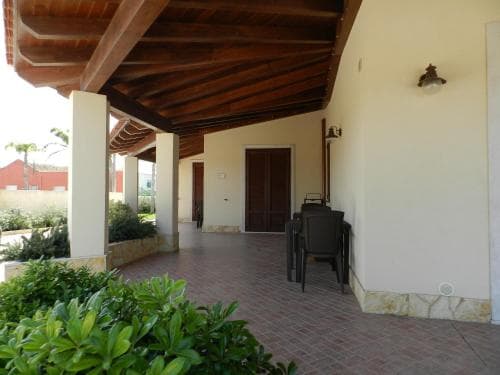 A serene outdoor patio with a tiled floor, wooden ceiling, and lush greenery offers a tranquil retreat for travelers seeking relaxation at a cozy accommodation.