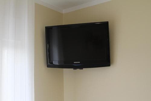A sleek Samsung TV mounted on a beige wall in a cozy corner of a modern living space, ideal for travelers seeking comfort and entertainment during their stay.