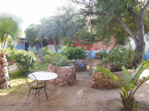 A serene outdoor garden with a small table and chairs surrounded by lush greenery and stone planters, ideal for a tranquil retreat or a cozy vacation spot.