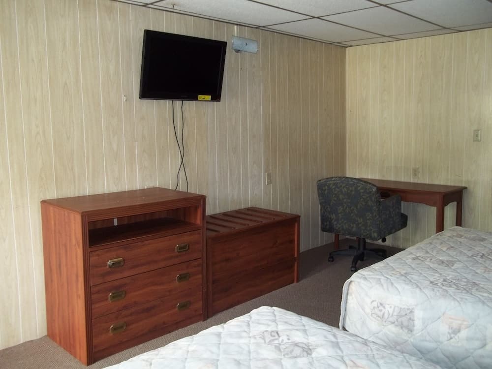 A cozy hotel room features wooden furnishings, a mounted TV, and a desk with an office chair, ideal for travelers seeking comfort and functionality.