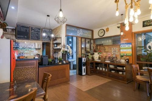 A cozy café interior with wooden furniture, vintage decor, and warm lighting creates an inviting atmosphere perfect for travelers seeking a relaxing spot to enjoy coffee and light bites.