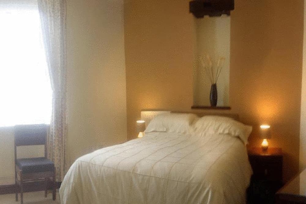 A cozy bedroom with soft lighting, a neatly made bed, and a serene ambiance is ideal for travelers seeking relaxation and comfort during their stay.
