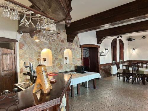 A cozy, rustic restaurant interior with stone walls, wooden beams, and warm lighting creates an inviting atmosphere, perfect for travelers seeking a traditional dining experience.