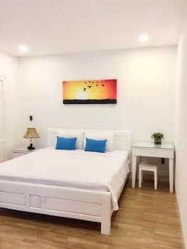 A cozy bedroom with minimalist decor, featuring a neatly made bed, vibrant sunset artwork, and soft lighting, creates a serene atmosphere ideal for travelers seeking relaxation and comfort.