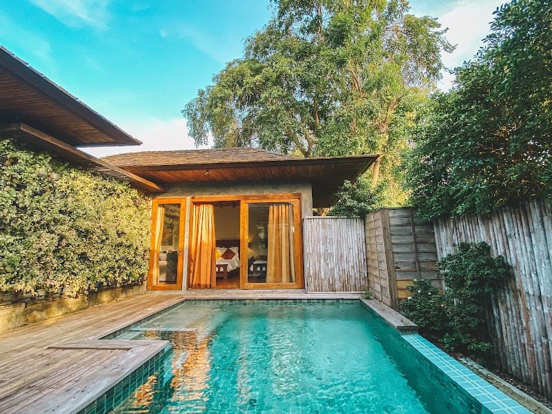 A serene beachside villa with a private pool surrounded by lush greenery offers a tranquil escape in Thailand, perfect for luxury travelers seeking relaxation.
