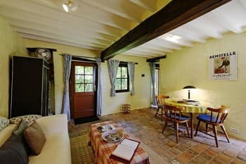 A cozy, rustic living room with wooden beams, brick flooring, and warm lighting creates an inviting atmosphere, perfect for travelers seeking a charming countryside retreat.