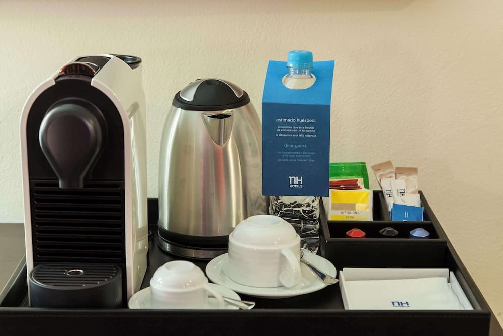 A cozy hotel room coffee station features a sleek espresso machine, stainless steel kettle, neatly arranged tea bags, and a welcoming note, ideal for travelers seeking comfort and convenience.