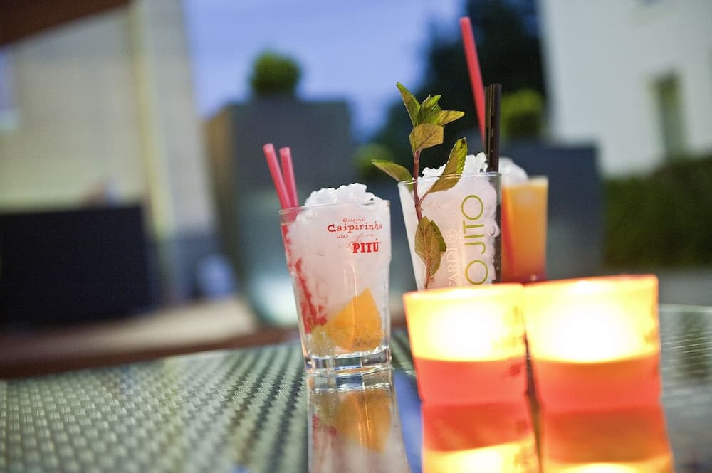 A cozy evening at an outdoor bar features vibrant cocktails like Caipirinha and Mojito, illuminated by warm candlelight, perfect for a relaxing night out.
