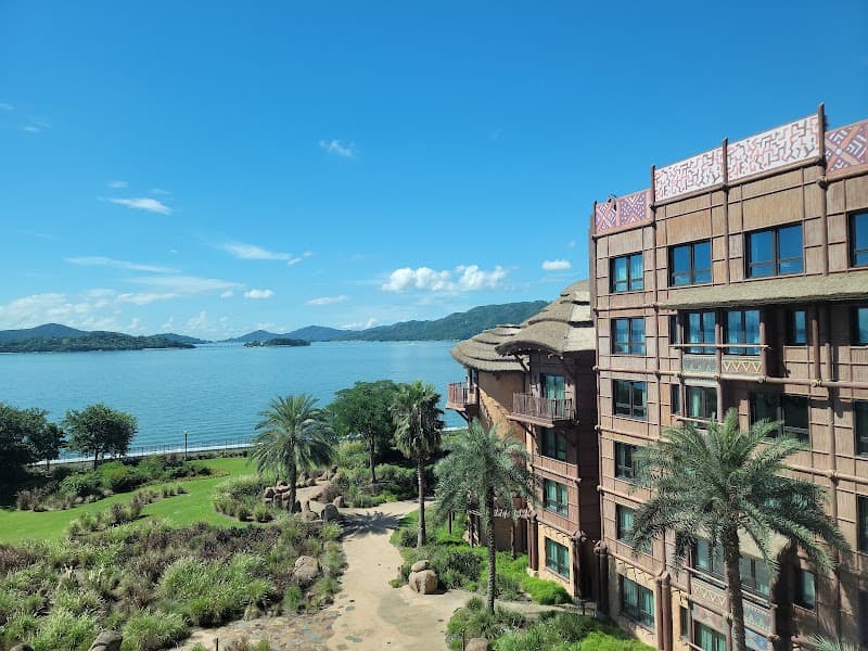 A serene tropical resort scene featuring lush greenery, palm trees, and a picturesque waterfront view under a clear blue sky, ideal for family vacations seeking relaxation and adventure.
