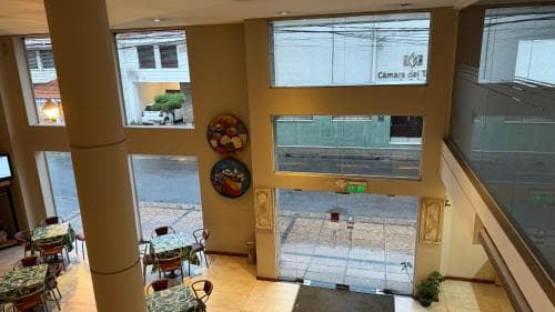 A cozy indoor café with vibrant tablecloths and decorative plates overlooks a bustling street through large windows, ideal for travelers seeking a relaxing spot to enjoy local ambiance.