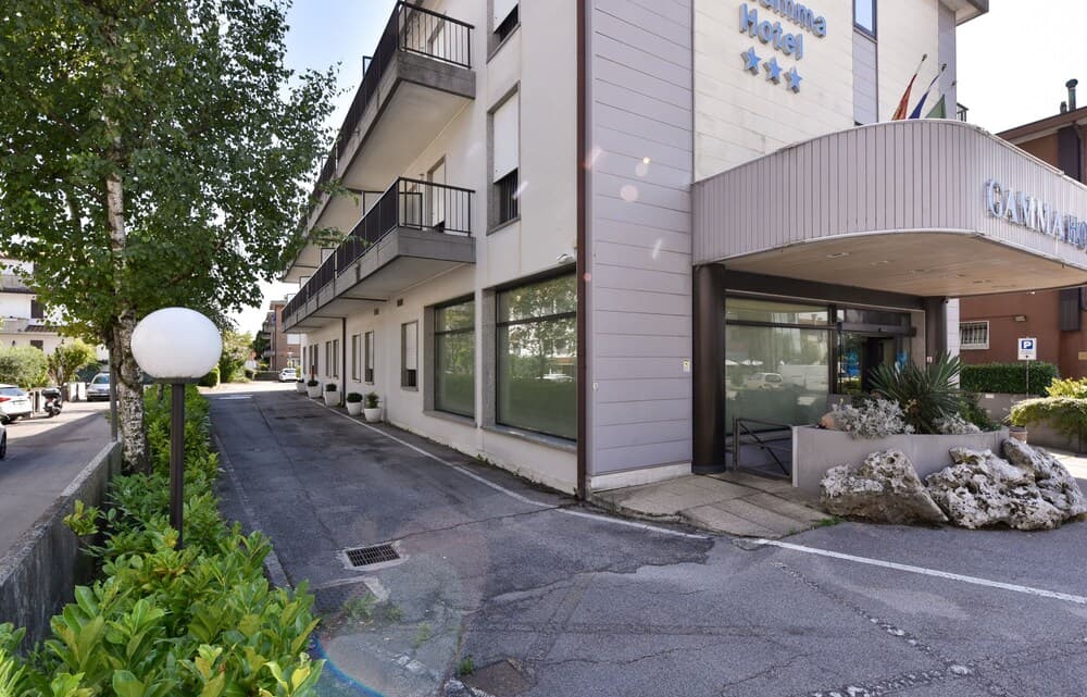A serene three-star hotel entrance features modern architecture, lush greenery, and a quiet driveway, ideal for travelers seeking a peaceful urban retreat.