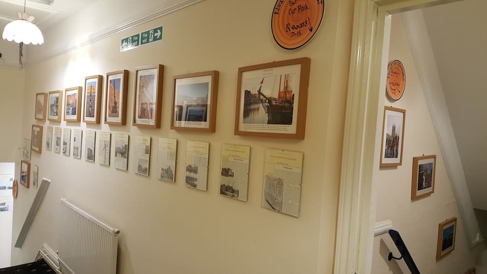 A cozy indoor hallway adorned with framed historical photos and informational plaques creates an inviting atmosphere for travelers exploring local heritage sites.