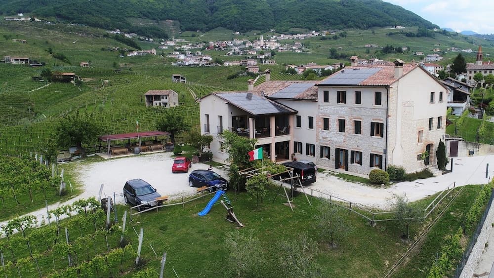 A charming rural villa surrounded by lush vineyards and rolling hills offers a serene getaway, complete with a playground and Italian flag, ideal for family vacations in picturesque countryside settings.