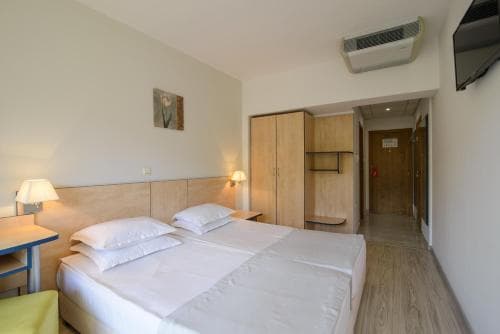 A cozy hotel room features a neatly made bed, wooden furnishings, and soft lighting, creating a welcoming atmosphere ideal for travelers seeking comfort and relaxation.
