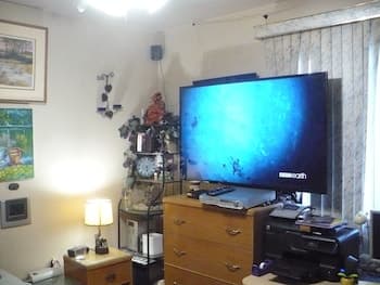 A cozy living room with a large TV displaying an underwater scene, surrounded by decorative shelves, framed artwork, and soft lighting, creates a serene atmosphere ideal for relaxation or a quiet evening at home.