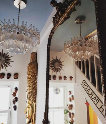 A vibrant boutique interior features eclectic decor with ornate mirrors, unique wall art, and a dazzling chandelier, creating an inviting atmosphere perfect for shoppers seeking distinctive home accents.