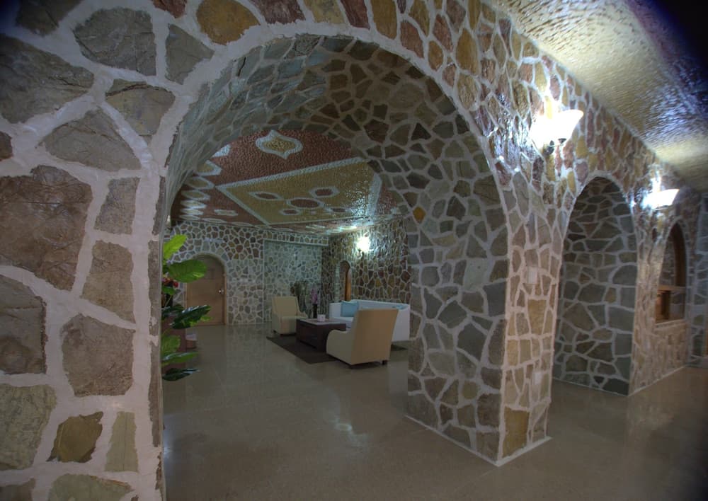 A cozy spa lounge features rustic stone arches, patterned ceilings, and plush seating, creating an inviting atmosphere ideal for relaxation and wellness retreats.