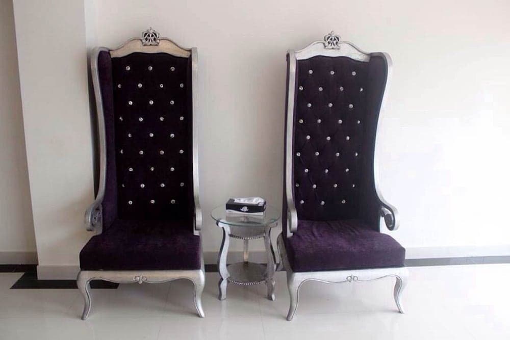 Elegant black velvet thrones with silver accents flank a glass side table in a minimalist indoor setting, ideal for event photography or luxurious interior design inspiration.