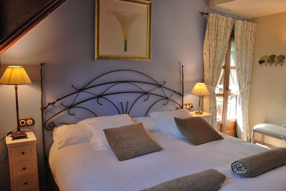 A cozy bedroom with a wrought iron bed, soft lighting from bedside lamps, floral curtains, and a serene ambiance ideal for a relaxing getaway.