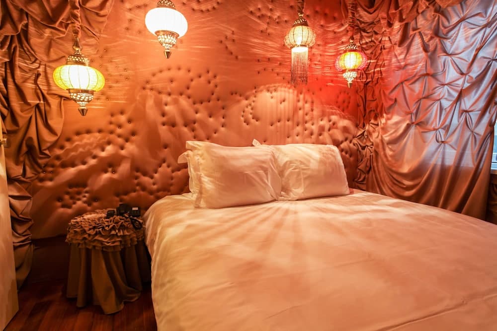 A luxurious bedroom with plush tufted walls, ornate lanterns, and a cozy bed invites travelers seeking a romantic and intimate retreat.