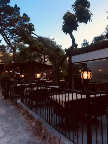A serene evening at an outdoor dining area surrounded by lush trees, featuring warm lanterns and a cozy ambiance, perfect for travelers seeking a tranquil dining experience in nature.