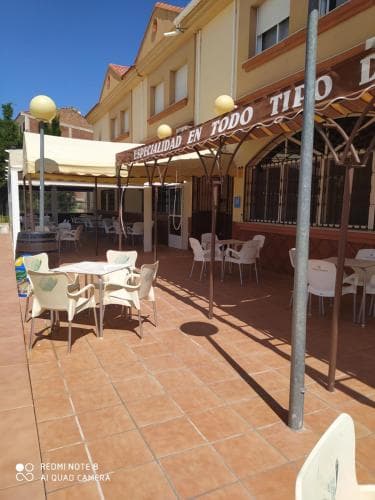 A sunny outdoor café with white chairs and tables under a tiled patio invites travelers to relax and enjoy meals in a warm, welcoming atmosphere perfect for leisurely dining or social gatherings.