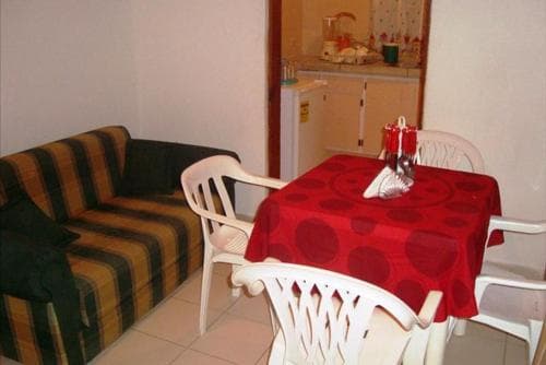 A cozy apartment interior features a striped sofa, a table with a red polka-dot tablecloth and white chairs, set against a backdrop of a kitchenette, ideal for travelers seeking a comfortable and budget-friendly stay.