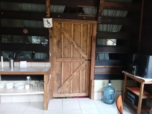 A rustic kitchen with a wooden barn-style door, tiled floor, and shelves creates a cozy, cabin-like atmosphere ideal for travelers seeking a quaint retreat.