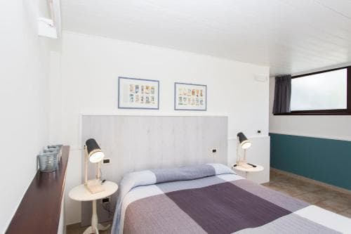 A cozy hotel room features a neatly made bed with purple bedding, framed artwork on the wall, and bedside lamps, creating a serene atmosphere ideal for travelers seeking relaxation.