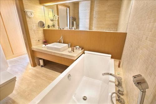 A serene hotel bathroom features a modern bathtub, sleek sink vanity, and warm lighting, ideal for travelers seeking relaxation and comfort during their stay.