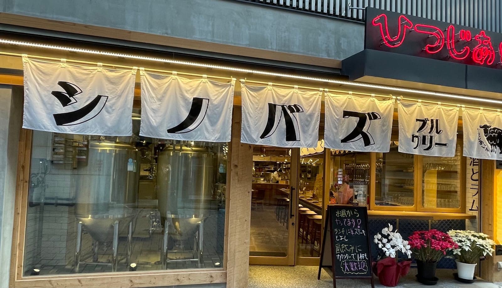 A cozy brewery in Tokyo's Ueno district invites travelers to enjoy craft beer with its inviting neon sign, wooden decor, and potted flowers, perfect for a relaxing evening out.