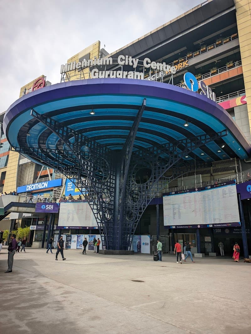The bustling Millennium City Centre in Gurugram features a modern, vibrant entrance with a striking blue canopy, ideal for travelers exploring shopping and entertainment hubs in India's urban landscape.