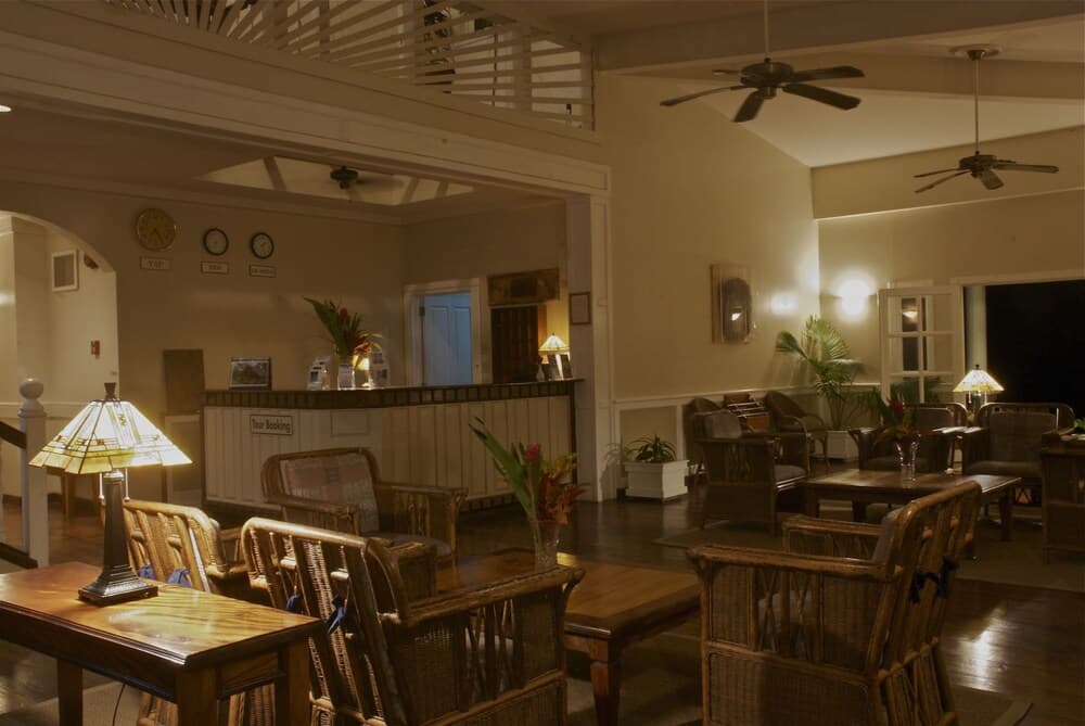 A cozy hotel lobby with warm lighting, wooden furniture, decorative clocks, and tropical plants creates an inviting atmosphere ideal for travelers seeking relaxation and comfort.