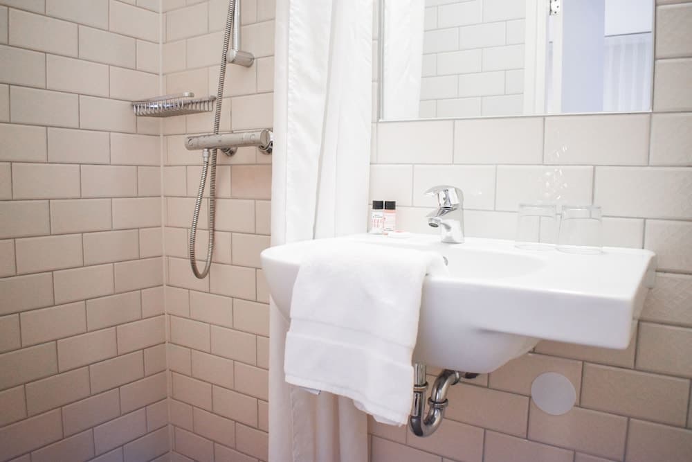 A clean, modern bathroom with white subway tiles, a sleek sink, and a shower area exudes a minimalist and refreshing vibe, ideal for travelers seeking comfort and hygiene in their accommodations.