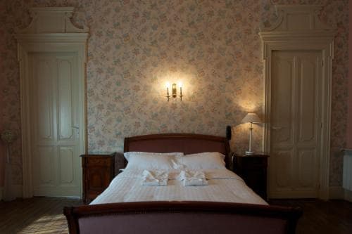 A cozy, vintage-style bedroom with floral wallpaper, wooden furniture, and soft lighting creates an inviting atmosphere, perfect for travelers seeking a charming and comfortable stay in a boutique hotel.