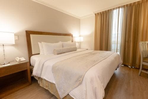 A cozy hotel room features a neatly made bed with plush pillows, warm wooden furnishings, and soft lighting, creating an inviting atmosphere ideal for travelers seeking comfort and relaxation.