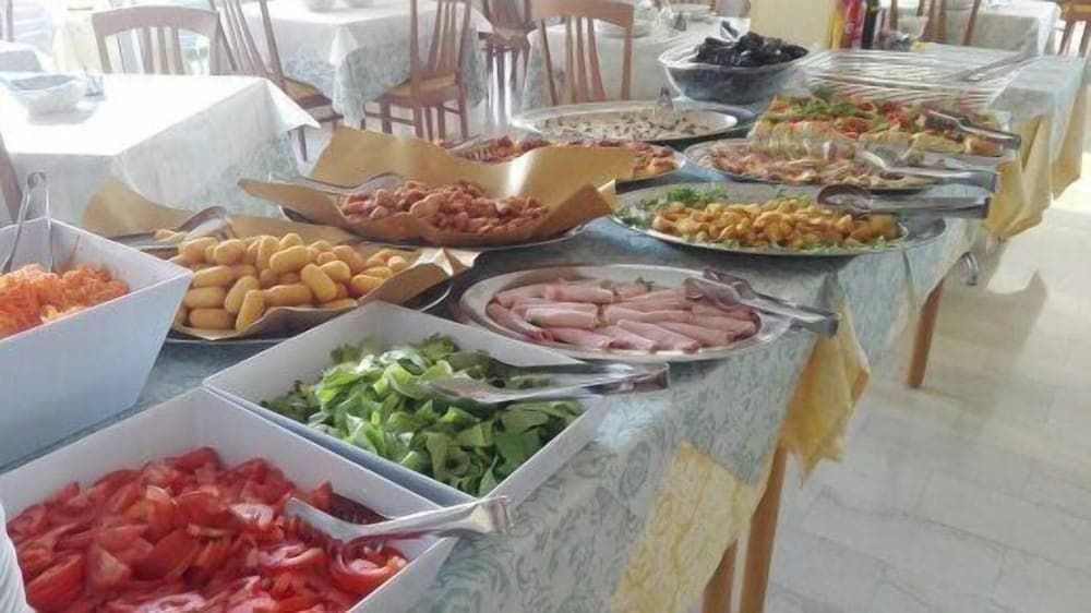 A vibrant buffet table laden with fresh vegetables, meats, and pastries invites travelers to indulge in a hearty meal at a cozy dining area, perfect for a relaxing culinary experience during a vacation.