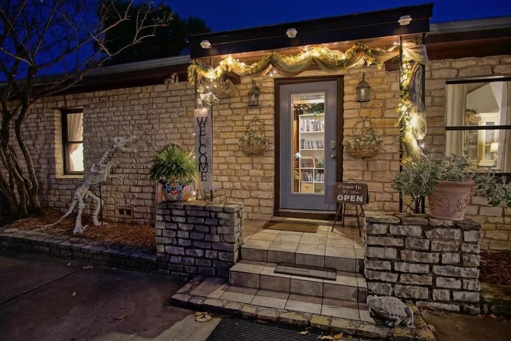 A cozy brick house entrance adorned with festive lights, garlands, and a playful skeleton decoration creates a welcoming autumnal atmosphere perfect for seasonal getaways.