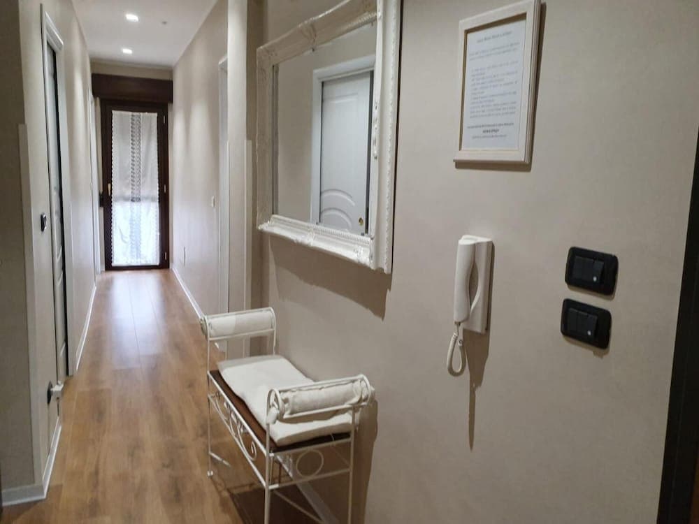 A cozy hotel hallway features warm wooden flooring, a cushioned bench, a wall-mounted phone, and a framed mirror, creating an inviting atmosphere for travelers seeking comfort and convenience.