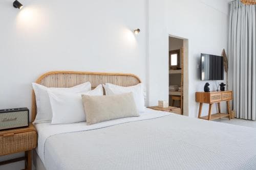 A serene hotel room features a cozy bed with white linens, bamboo furniture, and soft lighting, creating an inviting atmosphere ideal for relaxation and leisure travel.