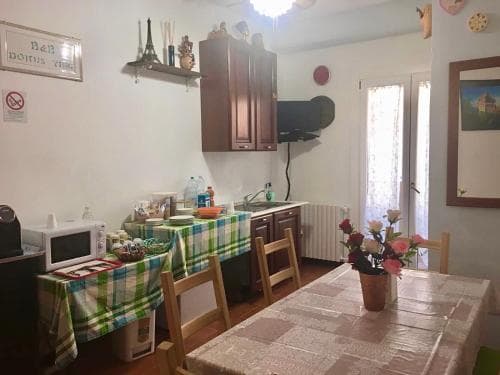 A cozy, rustic kitchen with wooden furniture, checkered tablecloths, and floral decorations creates a warm, inviting atmosphere ideal for travelers seeking a homely B&B experience.