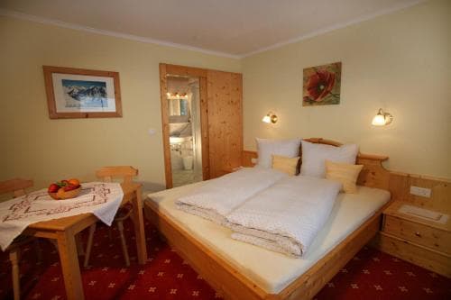 A cozy hotel room with wooden furnishings, a neatly made bed, and mountain-themed decor offers a warm and inviting atmosphere ideal for travelers seeking comfort in a rustic setting.
