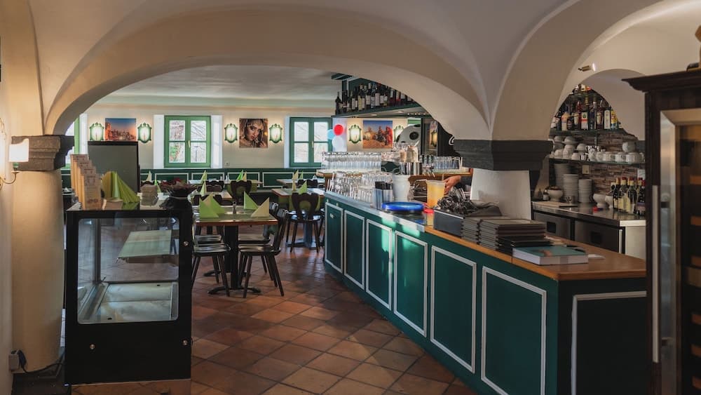 A cozy restaurant with arched ceilings, green accents, and terracotta flooring offers a charming ambiance ideal for travelers seeking a traditional dining experience.